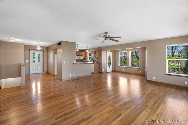 165 Four Winds Ct, Lake Ozark, MO 65049 - unfurnished living room with light wood-style floors, ceiling fan, baseboards, and a textured ceiling