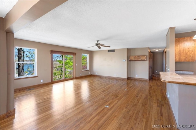 165 Four Winds Ct, Lake Ozark, MO 65049 - unfurnished living room with light wood-style floors, a ceiling fan, baseboards, and a textured ceiling