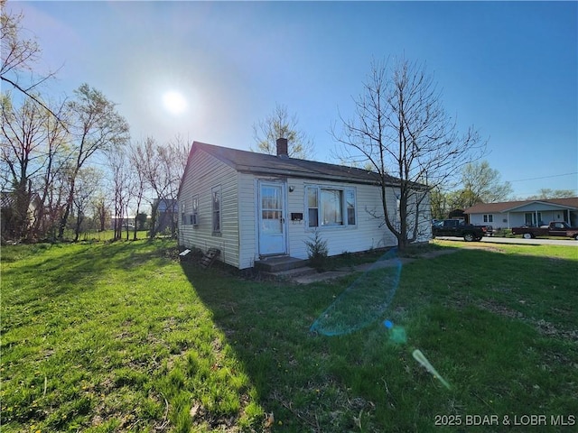 bungalow featuring a front yard, entry steps, and a chimney