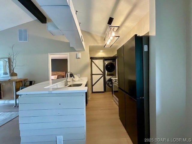 kitchen featuring stacked washer and dryer, light countertops, vaulted ceiling with beams, and visible vents