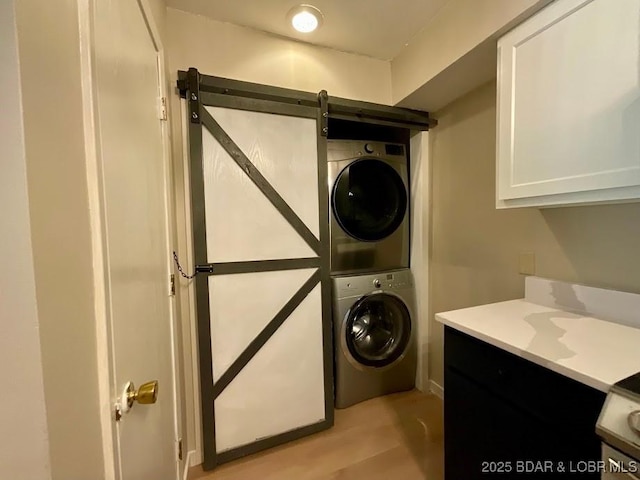 clothes washing area with laundry area, a barn door, and stacked washer / drying machine