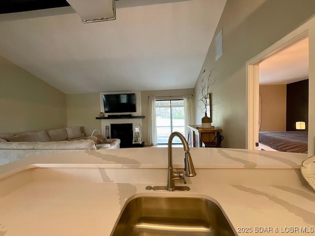 kitchen with a fireplace, vaulted ceiling, a sink, light countertops, and open floor plan