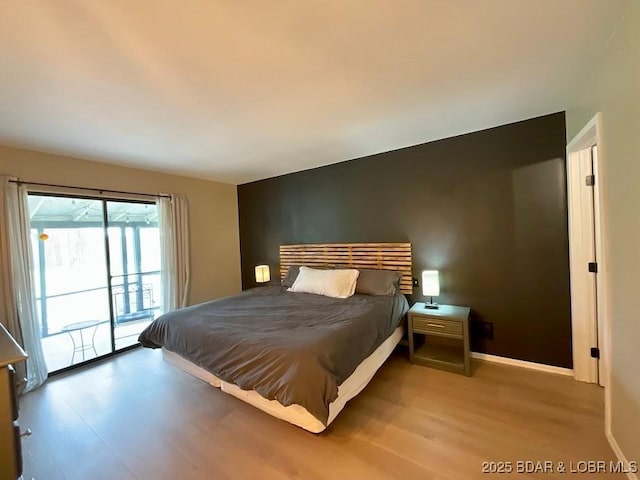 bedroom featuring access to outside, light wood finished floors, and baseboards