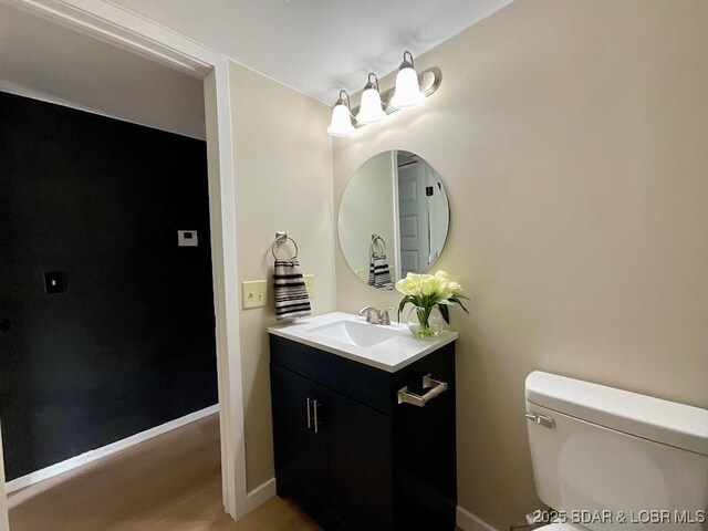 bathroom featuring toilet, vanity, and baseboards