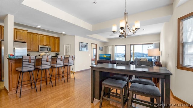 dining area with baseboards, a raised ceiling, a chandelier, light wood finished floors, and recessed lighting