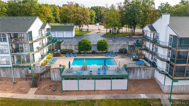 pool with a patio, fence, and stairway
