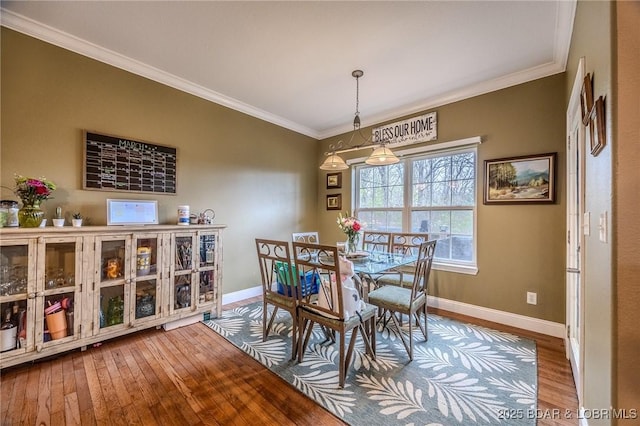 dining room featuring wood-type flooring, baseboards, and ornamental molding