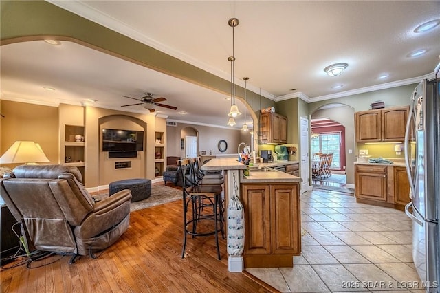 kitchen featuring open floor plan, arched walkways, freestanding refrigerator, and a peninsula
