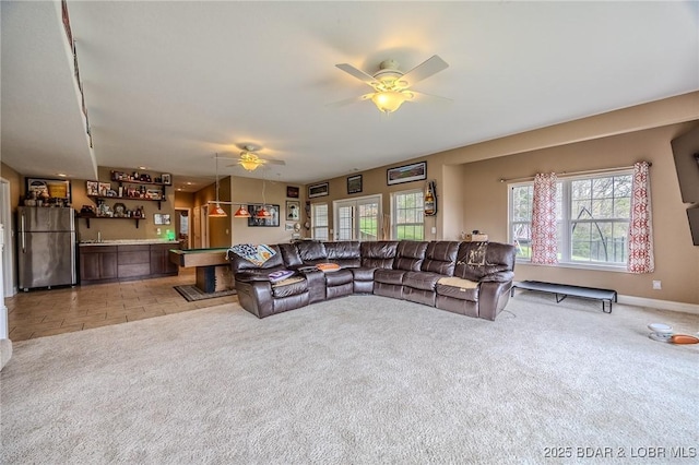 living area with bar area, light colored carpet, ceiling fan, and baseboards