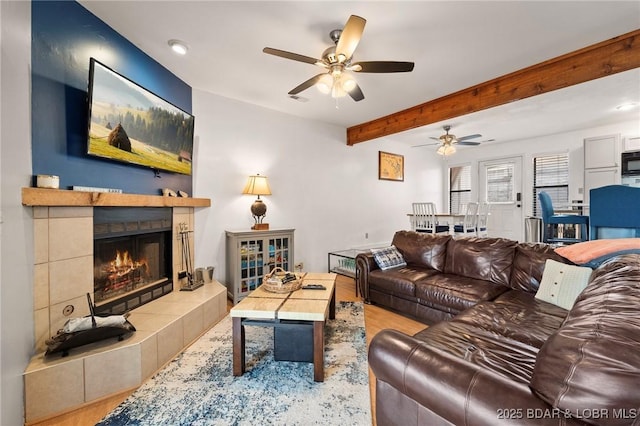 70 Ravenwood Dr, Lake Ozark, MO 65049 - living room featuring wood finished floors, a ceiling fan, a tile fireplace, and beam ceiling