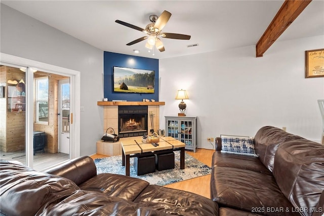 70 Ravenwood Dr, Lake Ozark, MO 65049 - living room with ceiling fan, wood finished floors, a tiled fireplace, and beam ceiling