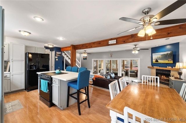 70 Ravenwood Dr, Lake Ozark, MO 65049 - kitchen with black appliances, a ceiling fan, open floor plan, a fireplace, and light wood finished floors