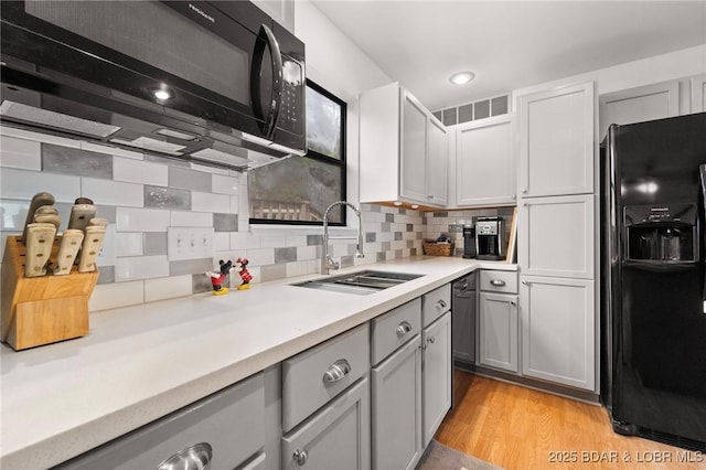 70 Ravenwood Dr, Lake Ozark, MO 65049 - kitchen featuring black appliances, light countertops, gray cabinets, tasteful backsplash, and light wood-style floors