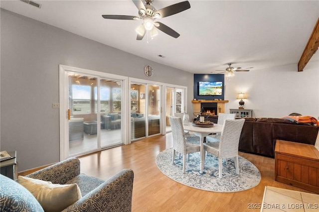 70 Ravenwood Dr, Lake Ozark, MO 65049 - dining area featuring a ceiling fan, a lit fireplace, and wood finished floors