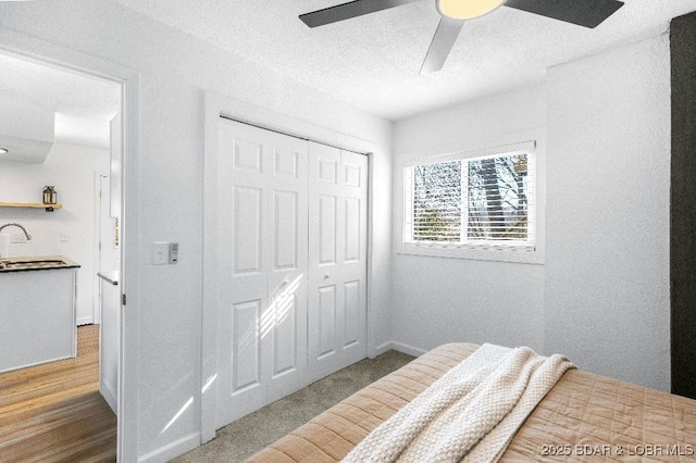 bedroom with a closet, a sink, a ceiling fan, a textured ceiling, and wood finished floors