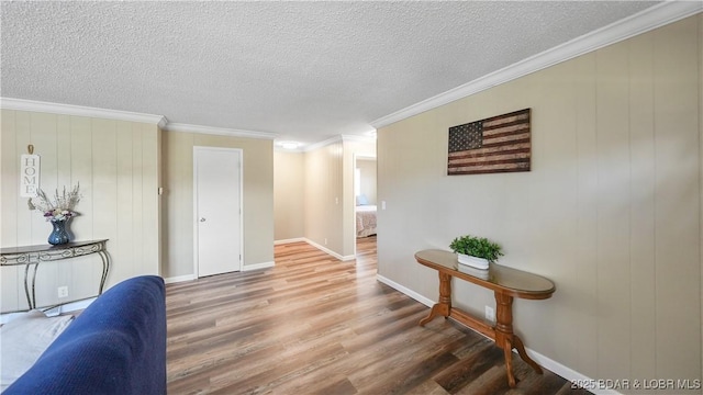 interior space with crown molding, a textured ceiling, wood finished floors, and baseboards