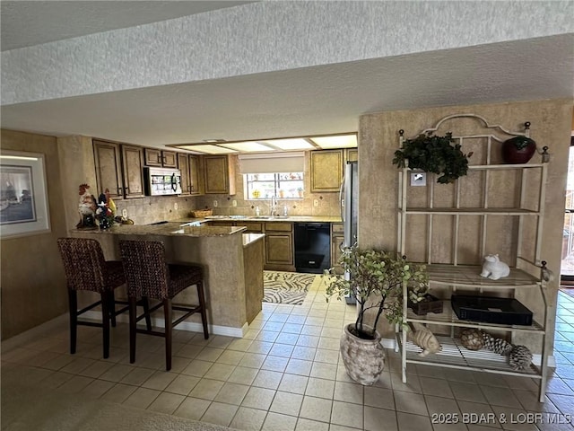 429-1D Racquet Club Dr Unit 1D, Four Seasons, MO 65049 - kitchen featuring light tile patterned floors, brown cabinetry, a peninsula, dishwasher, and stainless steel microwave