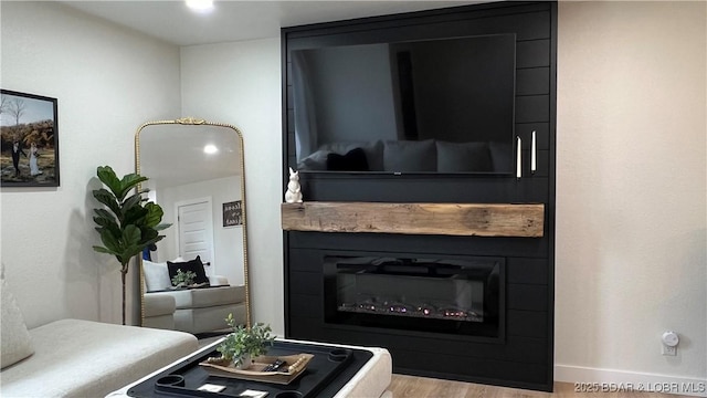 detailed view of a large fireplace, wood finished floors, and baseboards