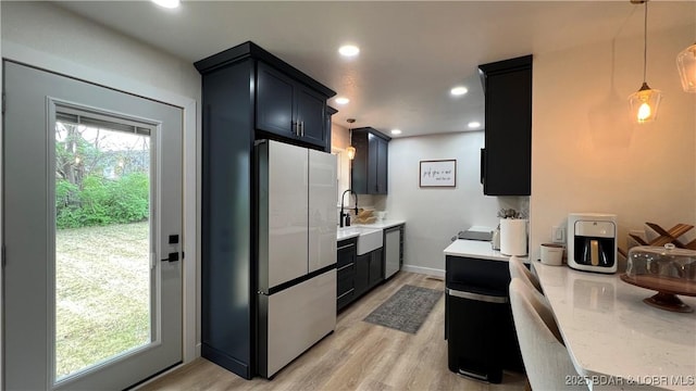 kitchen with dishwasher, freestanding refrigerator, light wood finished floors, a sink, and recessed lighting