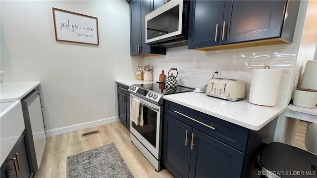 kitchen featuring electric stove, decorative backsplash, light wood-type flooring, blue cabinets, and baseboards