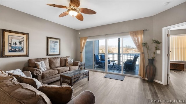 living area featuring baseboards, ceiling fan, and wood finished floors