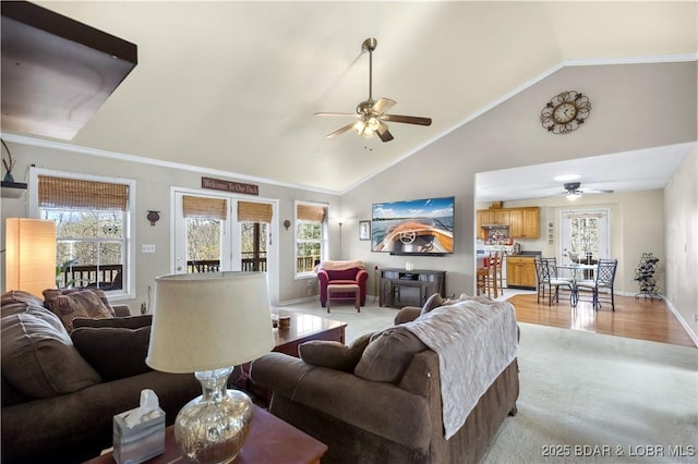 living area featuring baseboards, light wood-style floors, ceiling fan, and high vaulted ceiling