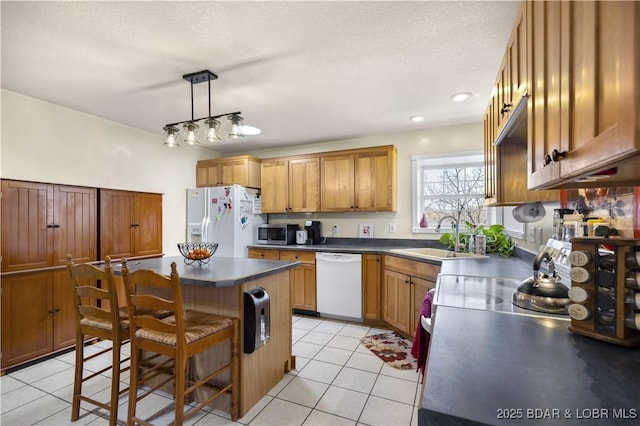kitchen featuring white appliances, light tile patterned flooring, a sink, and a breakfast bar area
