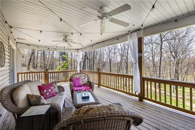 wooden terrace with a ceiling fan and outdoor lounge area