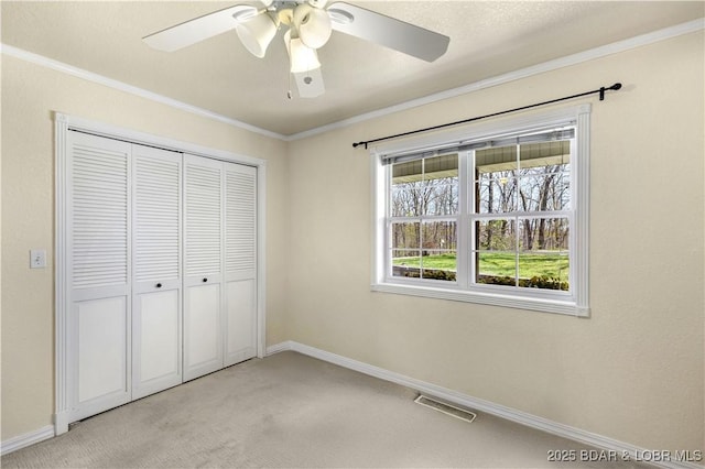 unfurnished bedroom with baseboards, ornamental molding, light carpet, and a closet