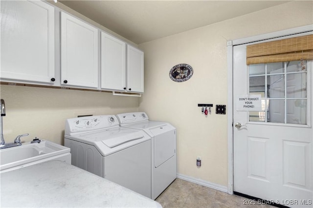 washroom with a sink, separate washer and dryer, baseboards, and cabinet space