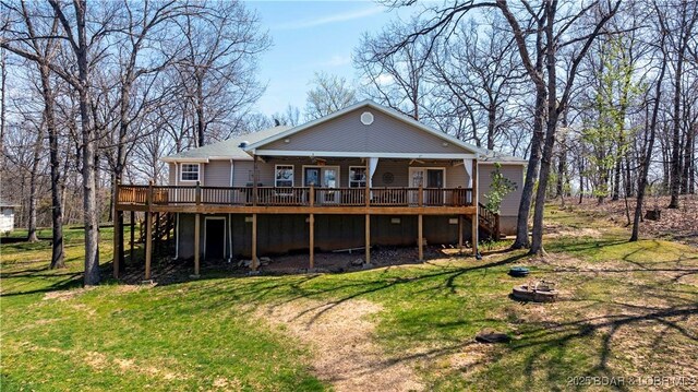 rear view of house featuring ceiling fan, a fire pit, a wooden deck, a yard, and stairway
