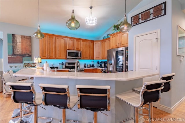 5218 Big Ship St, Osage Beach, MO 65065 - kitchen featuring a breakfast bar, light countertops, lofted ceiling, light wood finished floors, and appliances with stainless steel finishes