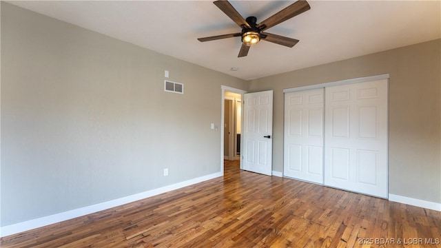 unfurnished bedroom featuring baseboards, wood finished floors, a closet, and ceiling fan