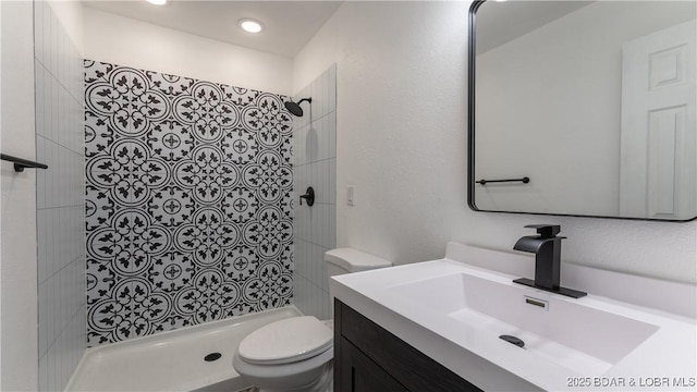 bathroom with a shower stall, toilet, and vanity