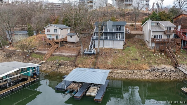 dock featuring stairs, boat lift, a residential view, and a deck with water view