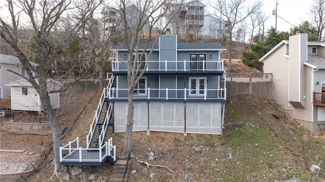 back of house with a balcony, stairway, and a chimney
