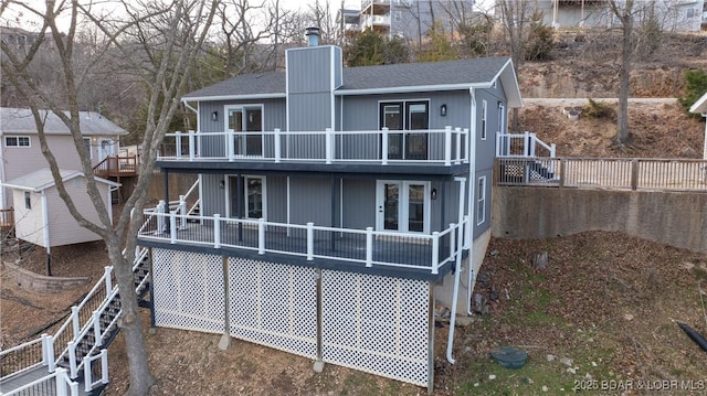 rear view of house featuring a shingled roof, a deck, and a chimney