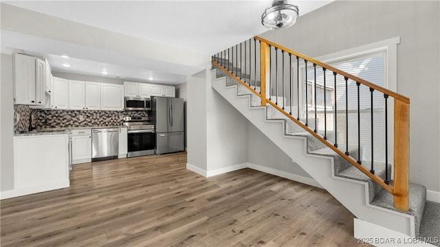 1129 Ginger Rd, Lake Ozark, MO 65049 - kitchen featuring appliances with stainless steel finishes, light wood-style flooring, white cabinetry, tasteful backsplash, and recessed lighting