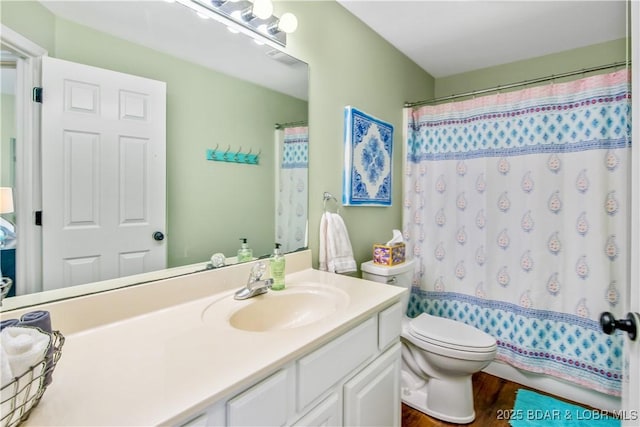 bathroom with toilet, vanity, wood finished floors, and curtained shower