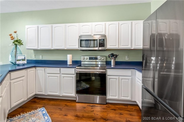 kitchen featuring stainless steel appliances, white cabinets, and dark countertops
