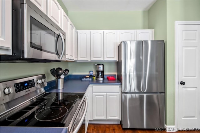 kitchen with appliances with stainless steel finishes, white cabinetry, dark countertops, and dark wood-style flooring