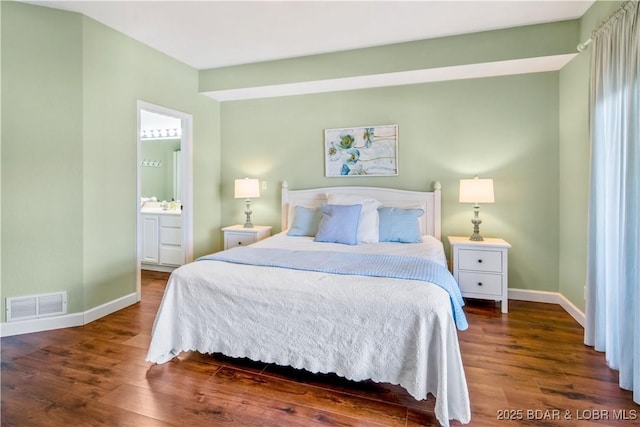 bedroom with wood finished floors, baseboards, and ensuite bath