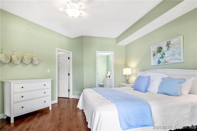 bedroom featuring dark wood-style floors, ensuite bathroom, and baseboards