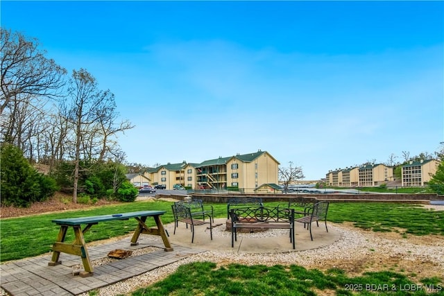 view of property's community featuring a lawn, a residential view, and a patio