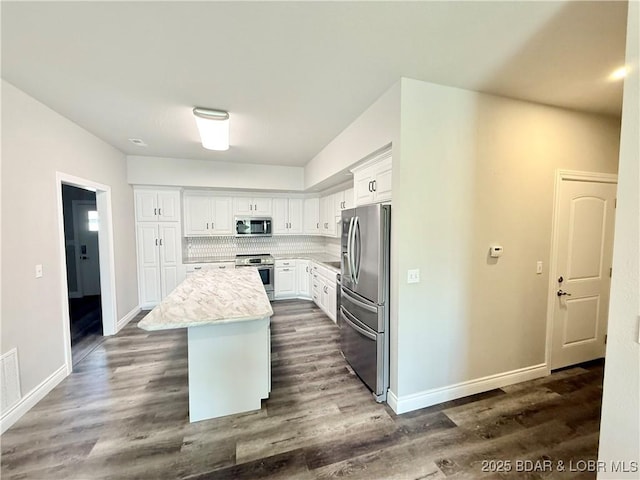245 Davis Dr, Holts Summit, MO 65043 - kitchen featuring white cabinets, dark wood finished floors, a kitchen island, baseboards, and appliances with stainless steel finishes