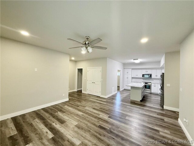 245 Davis Dr, Holts Summit, MO 65043 - unfurnished living room featuring baseboards, recessed lighting, ceiling fan, and dark wood-style flooring