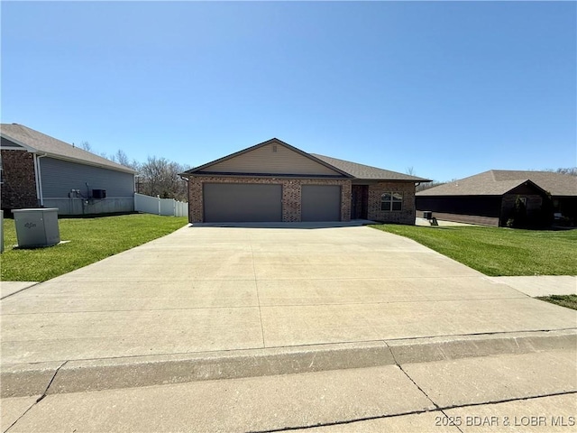 245 Davis Dr, Holts Summit, MO 65043 - single story home featuring a front lawn, driveway, fence, brick siding, and an attached garage