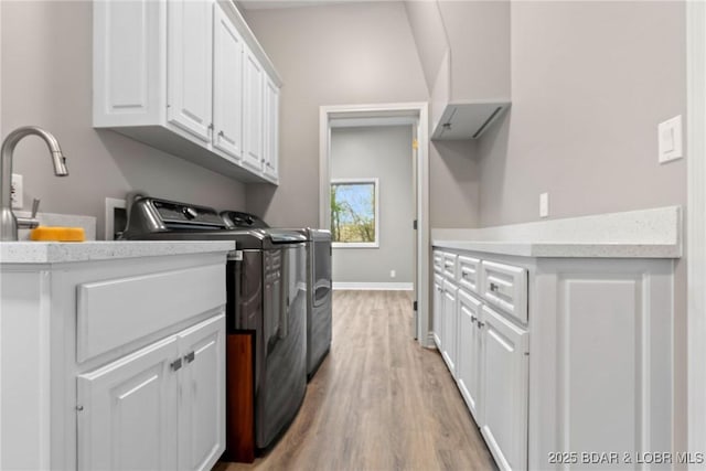 275 Waterford Ter, Sunrise Beach, MO 65079 - clothes washing area with a sink, washing machine and clothes dryer, baseboards, cabinet space, and light wood-style flooring
