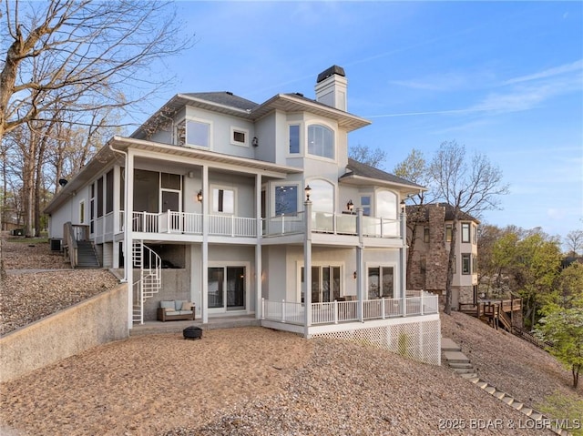 275 Waterford Ter, Sunrise Beach, MO 65079 - rear view of house featuring stairway, a chimney, a balcony, stucco siding, and a patio area