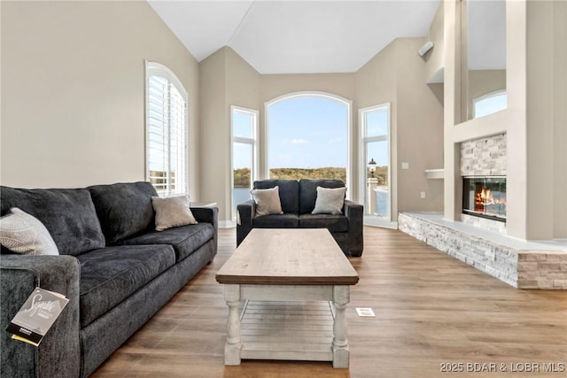 275 Waterford Ter, Sunrise Beach, MO 65079 - living room featuring vaulted ceiling, a glass covered fireplace, and wood finished floors